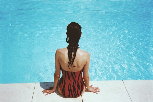 woman sitting next to swimming pool during summer