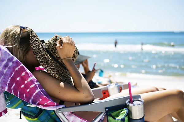 woman sun bathing near oceanside on beach in the summer