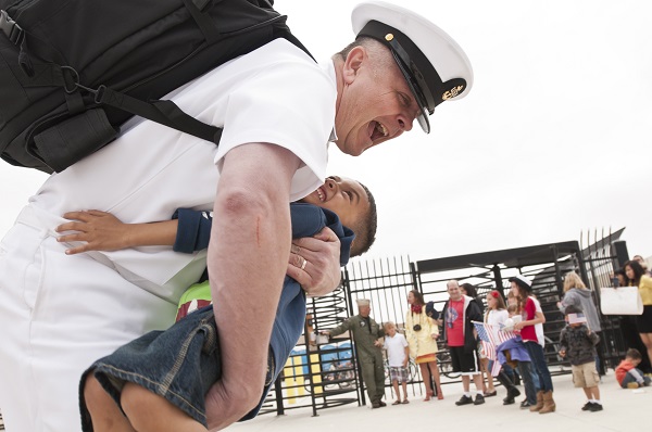 Military father hugs son after reuniting. 