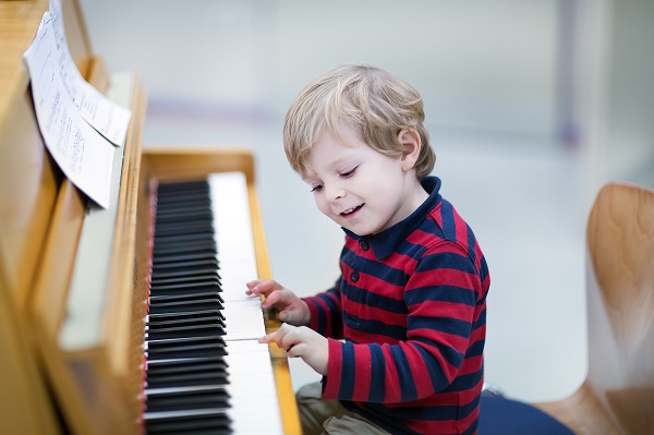 Little boy playing wooden instrument piano 