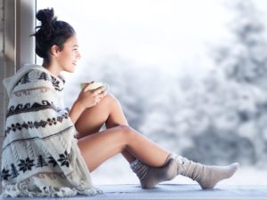 Woman sips tea in dry air during cold winter.