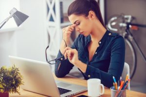 Woman has headache at desk in office due to dry air