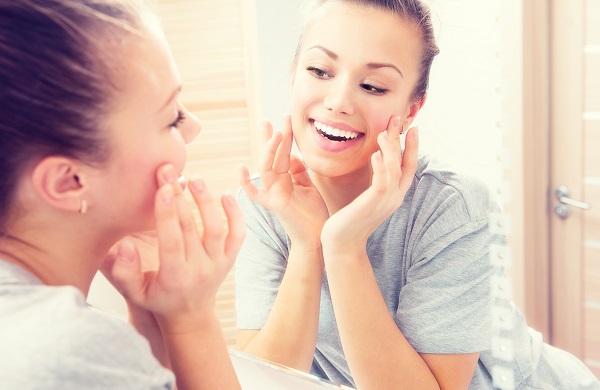 Woman inspects skin in mirror 