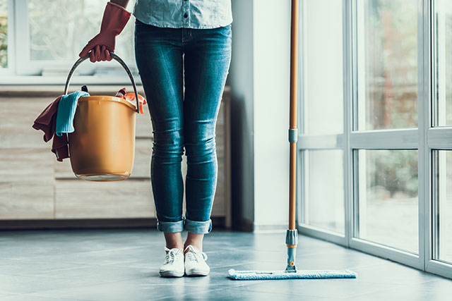 Woman with cleaning bucket and mop in her hands to counteract allergies by cleaning.