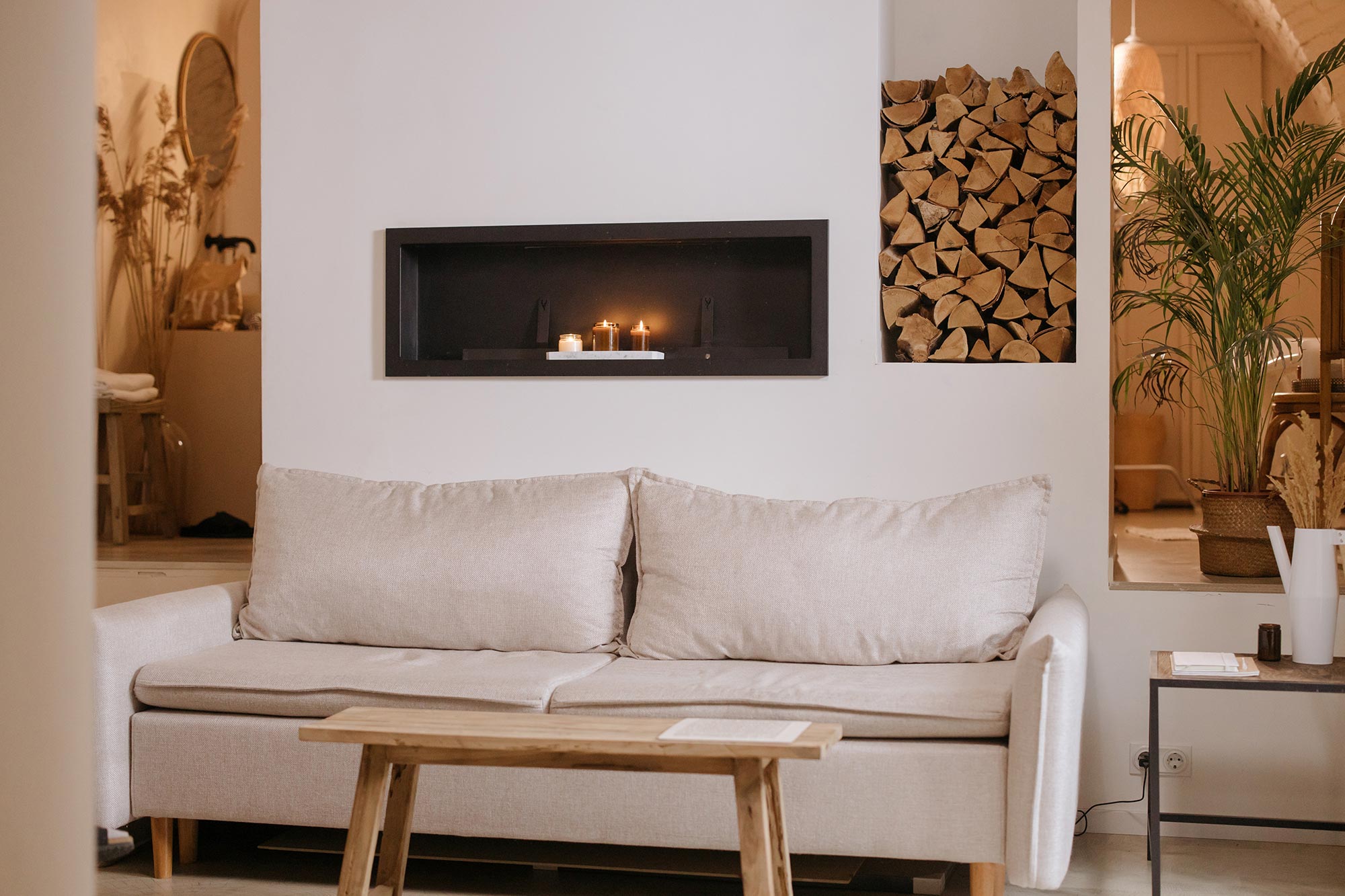 Salle de séjour confortable avec alcôve, bougies et tas de bois.